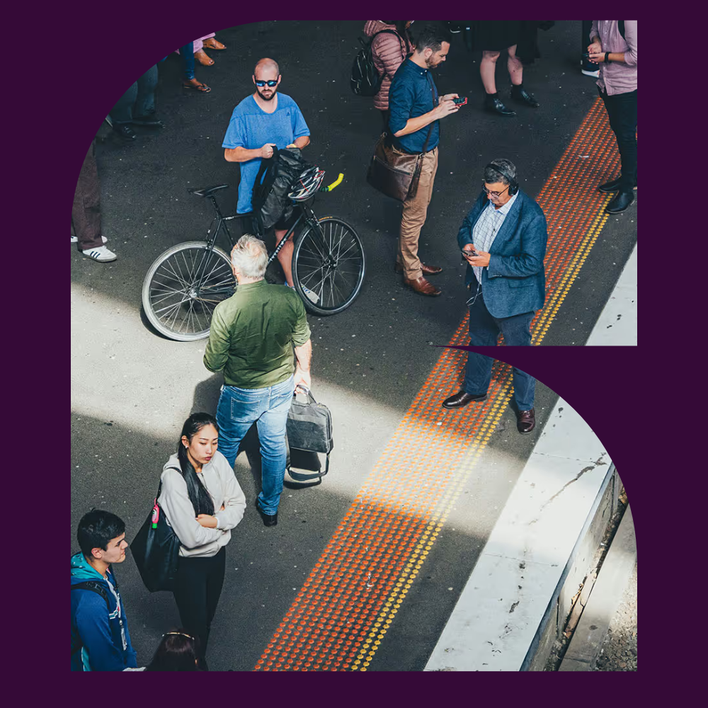 Commuters waiting on a train station platform near tactile paving.