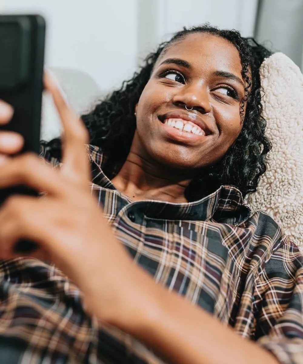 An image of a women on her phone, smiling.