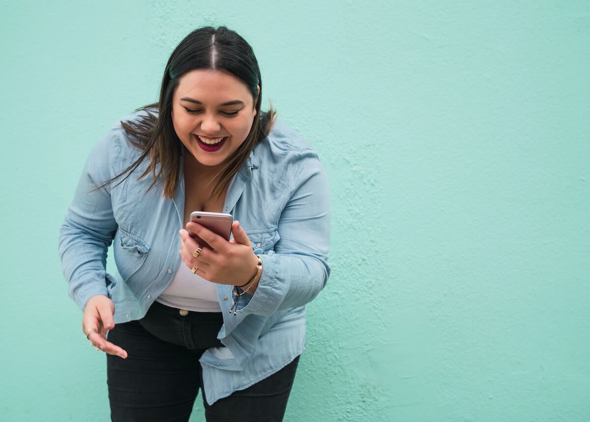 An image of a women on her phone, smiling.