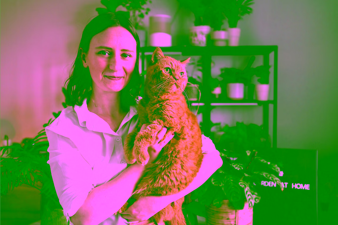 Une femme porte et câline son chat dans son salon.