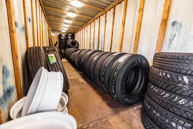 Tire service tire inventory with rows of commercial truck tires and wheels stored for heavy-duty replacements. Kumho branding is visible on the front tire.