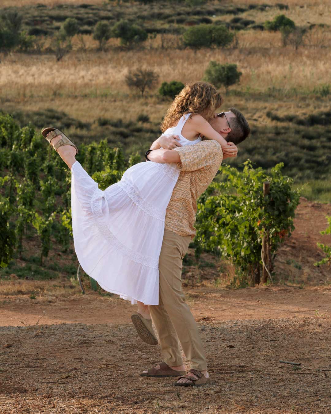 A man picking up his bride in a vineyard
