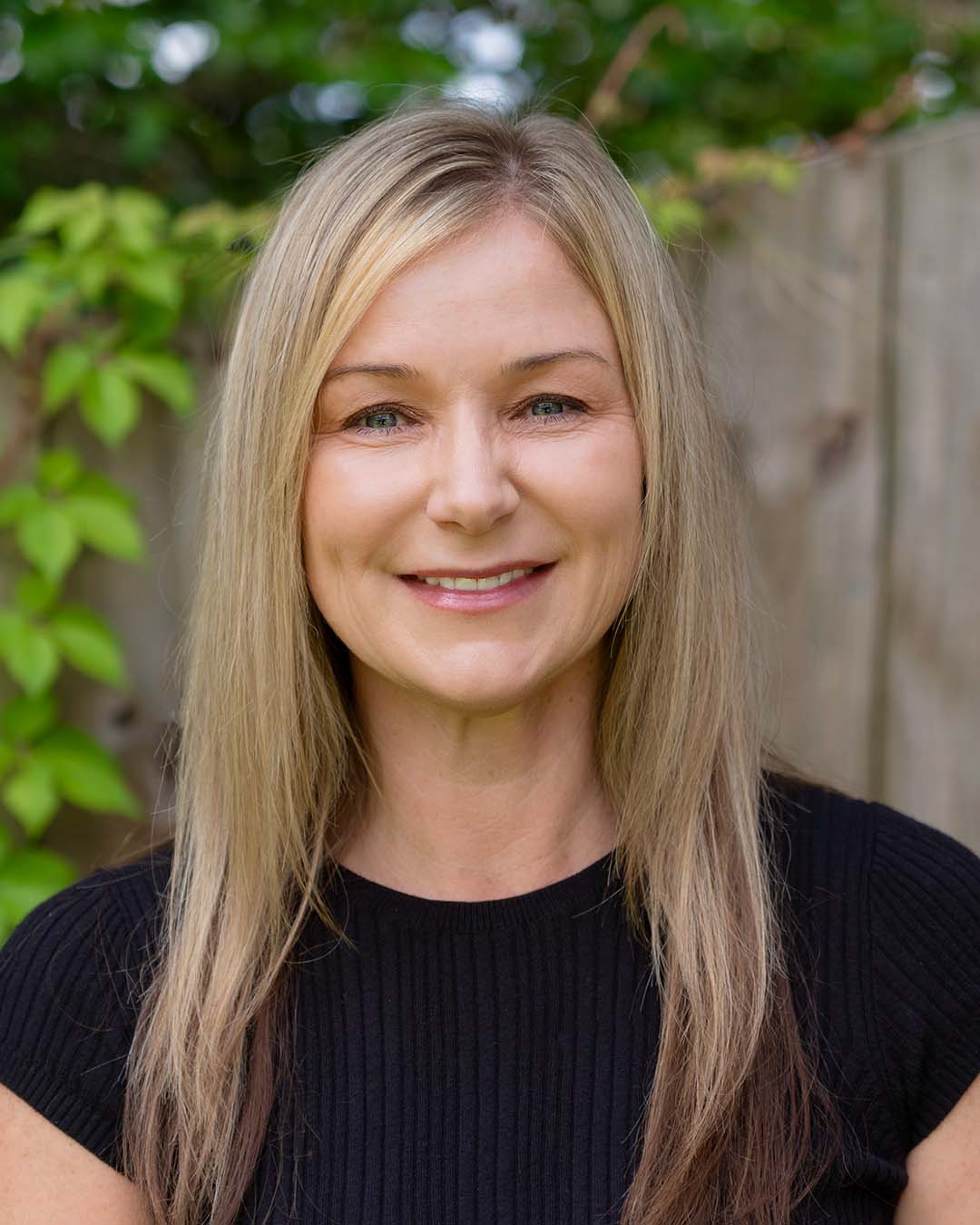 Professional headshot of a woman with blond hair wearing a black shirt