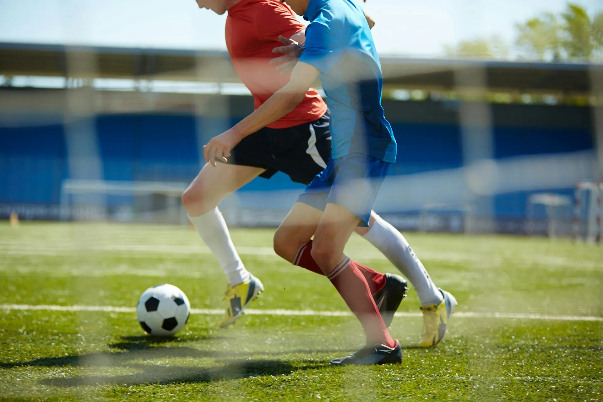 Two young boys playing soccer. They're chasing a ball.