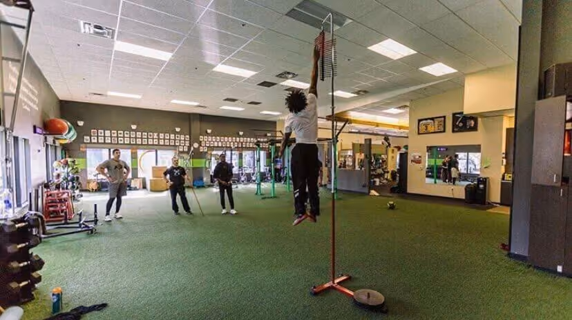 Group of men looking at a man wearing shirt doing vertical jump