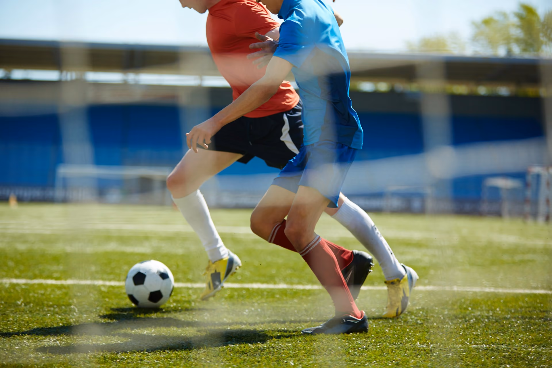 Two young boys playing soccer. They're chasing a ball.