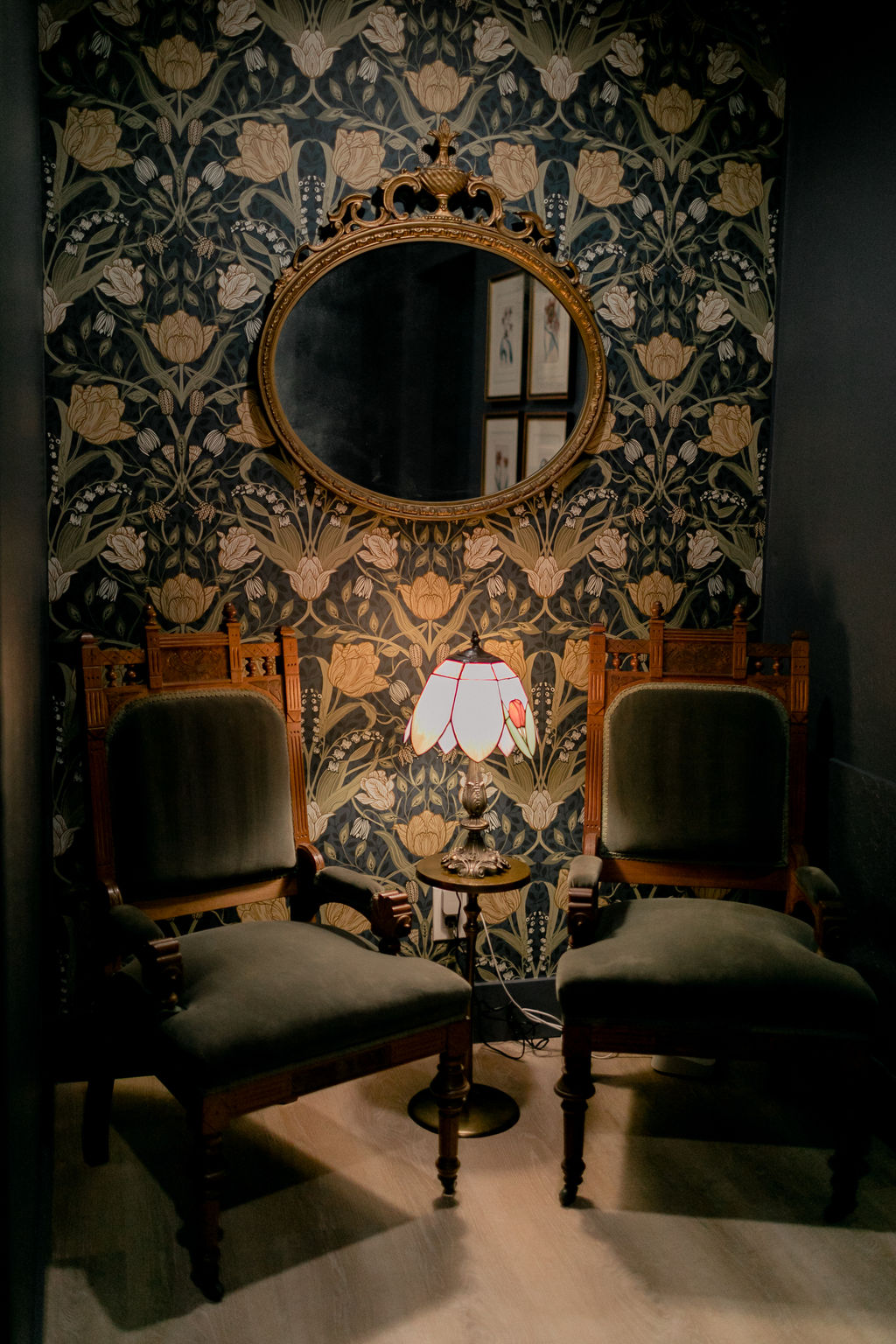White shelving unit with decorative bottles, glasses, flower vase, framed tree print, cut lemons, and stacked books.