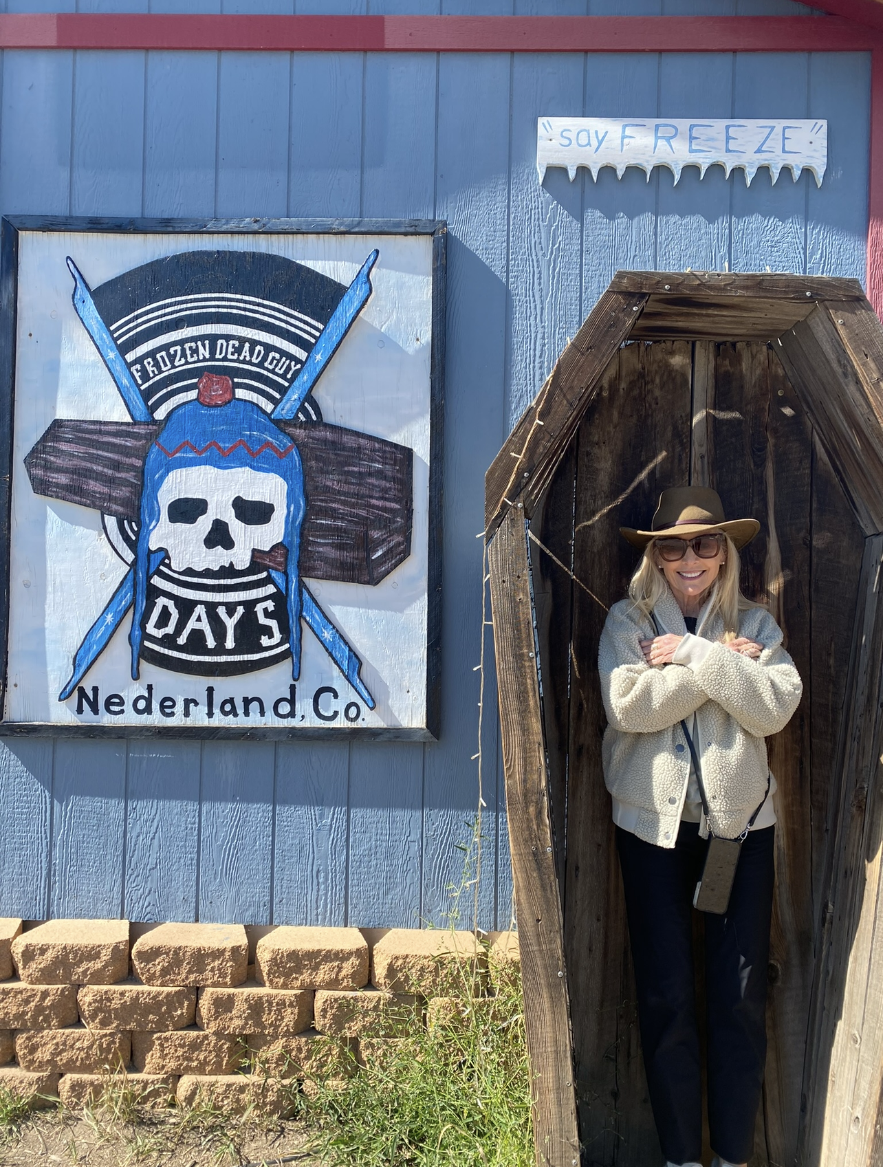 Woman posing in a coffin with a painting of a frozen dead guy in Nederland, Colorado