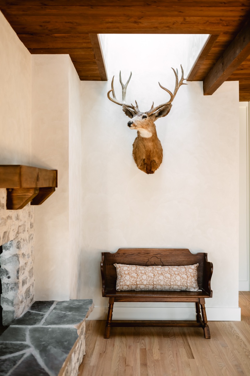 Cozy kitchen with wooden cabinets, granite island countertop with three chairs, and various kitchen items including pans hanging above the island and decorative gnomes on cabinet tops.