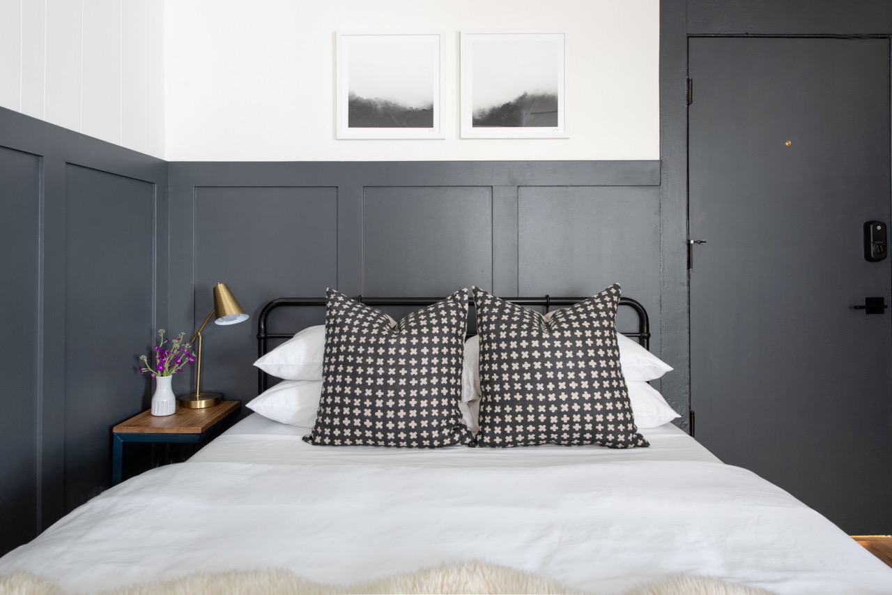 Dimly lit hallway with dark walls, wood floors, a patterned rug, and double glass doors at the end.