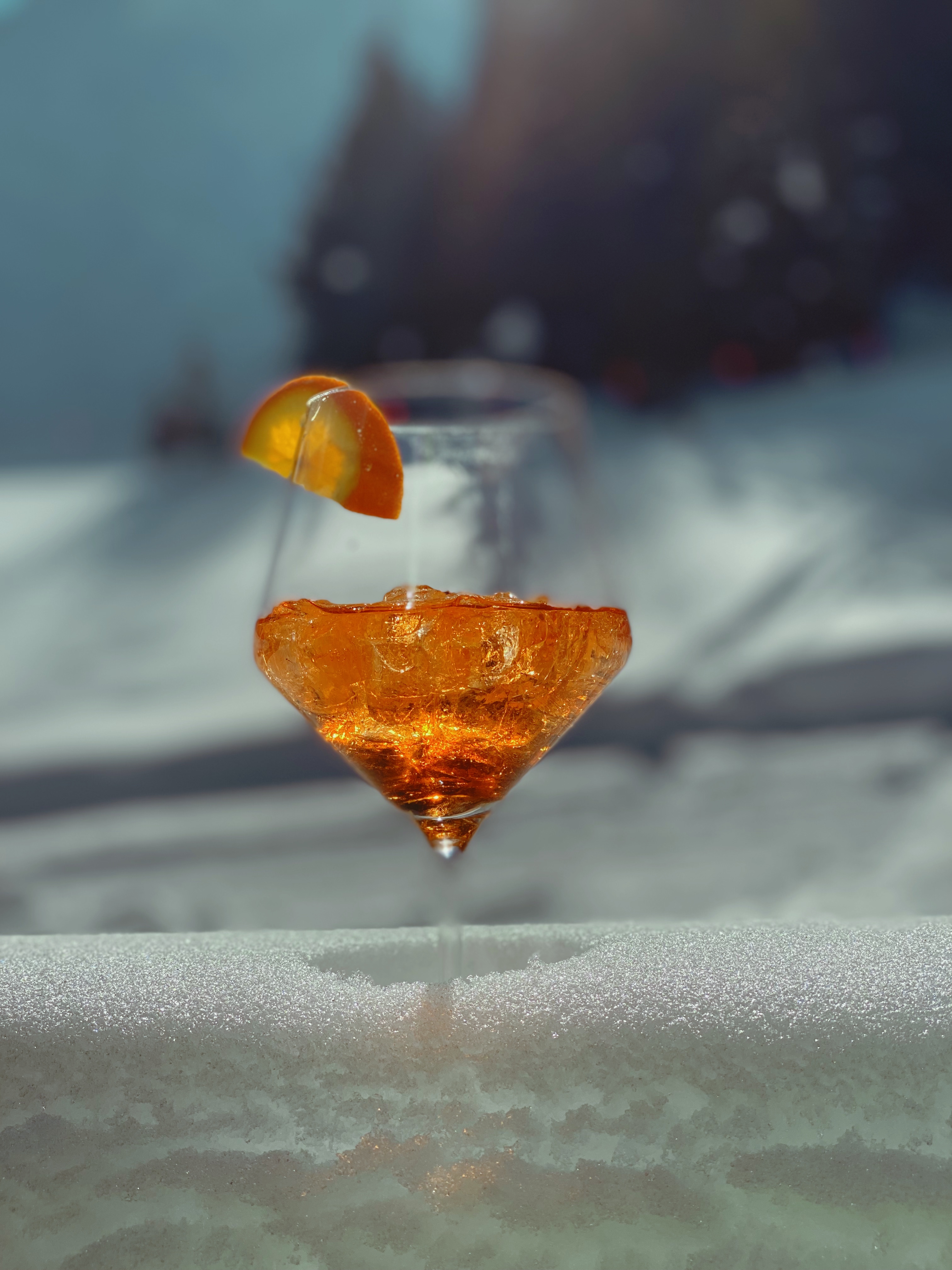 Several glasses of aperol spritz cocktails with ice and garnished with small white flowers on a wooden table.