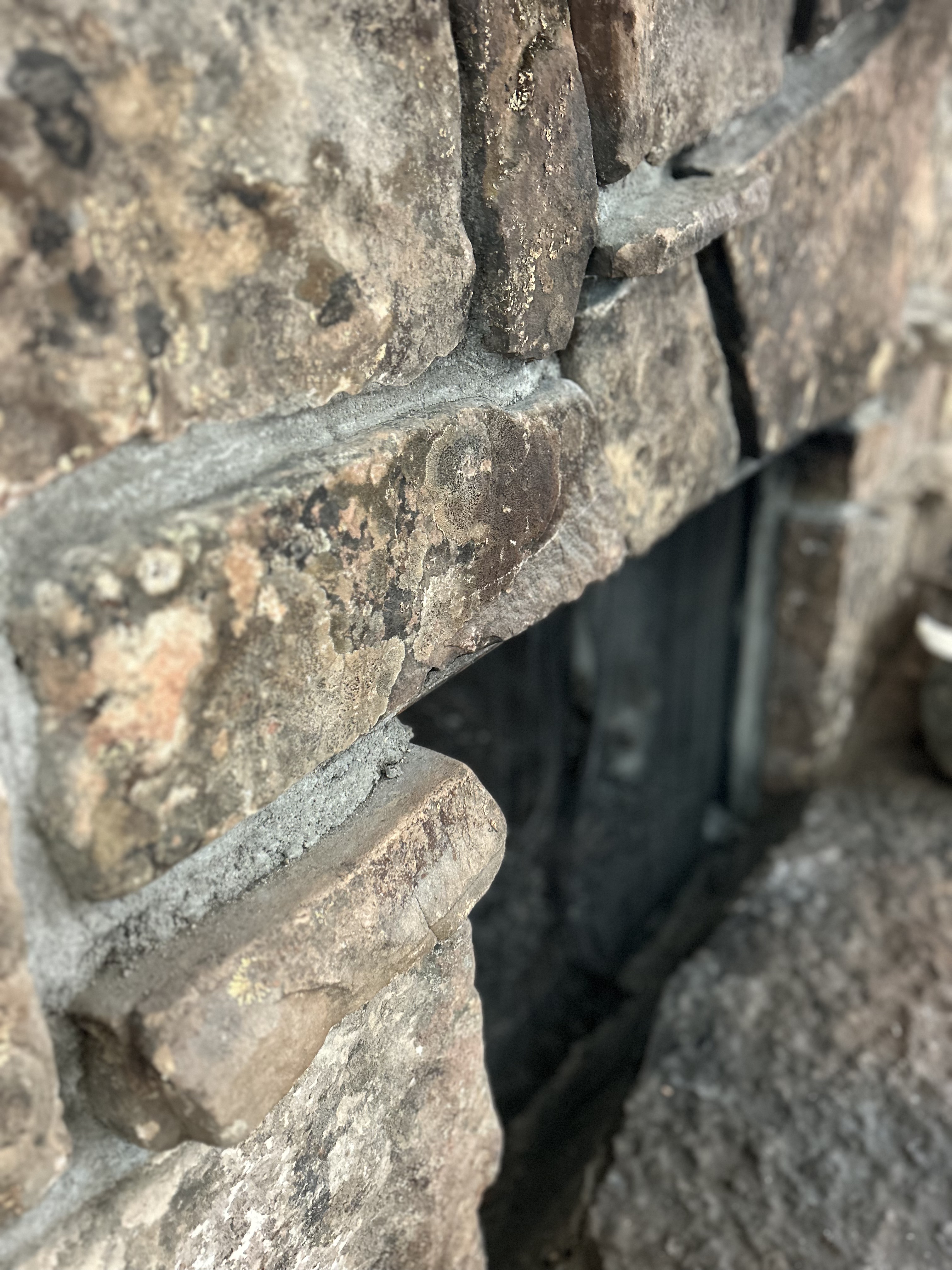 Close-up of a rustic stone wall with weathered, textured stones and mortar in natural earthy tones.