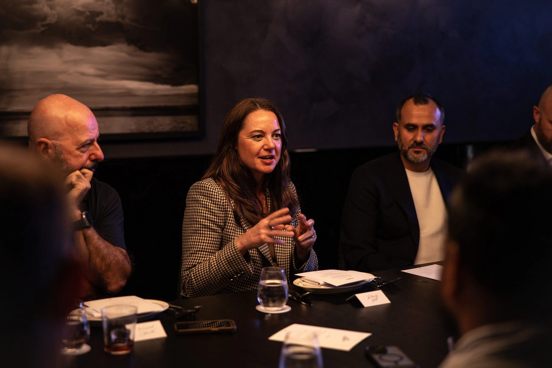 Three people sitting at a table engaged in a discussion during a meeting.