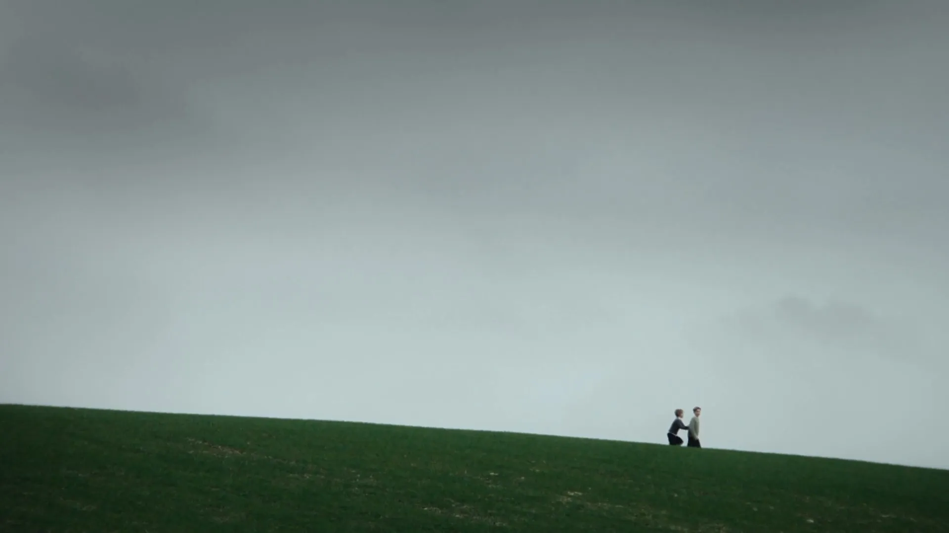 A still from a Superbeam video, two boys running on a field with a bright grey sky.
