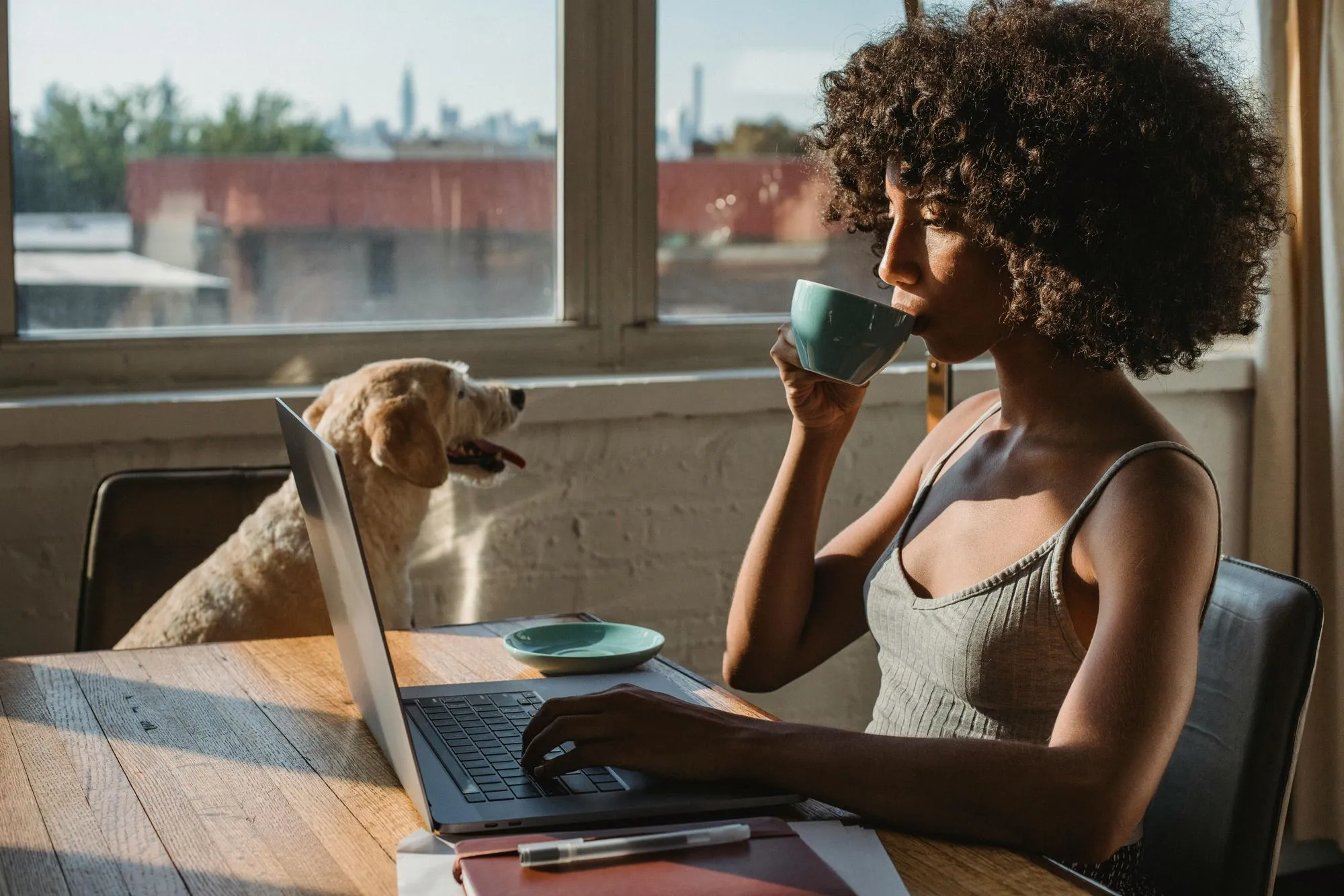Femme qui travaille sur un ordinateur portable à une table près de la fenêtre