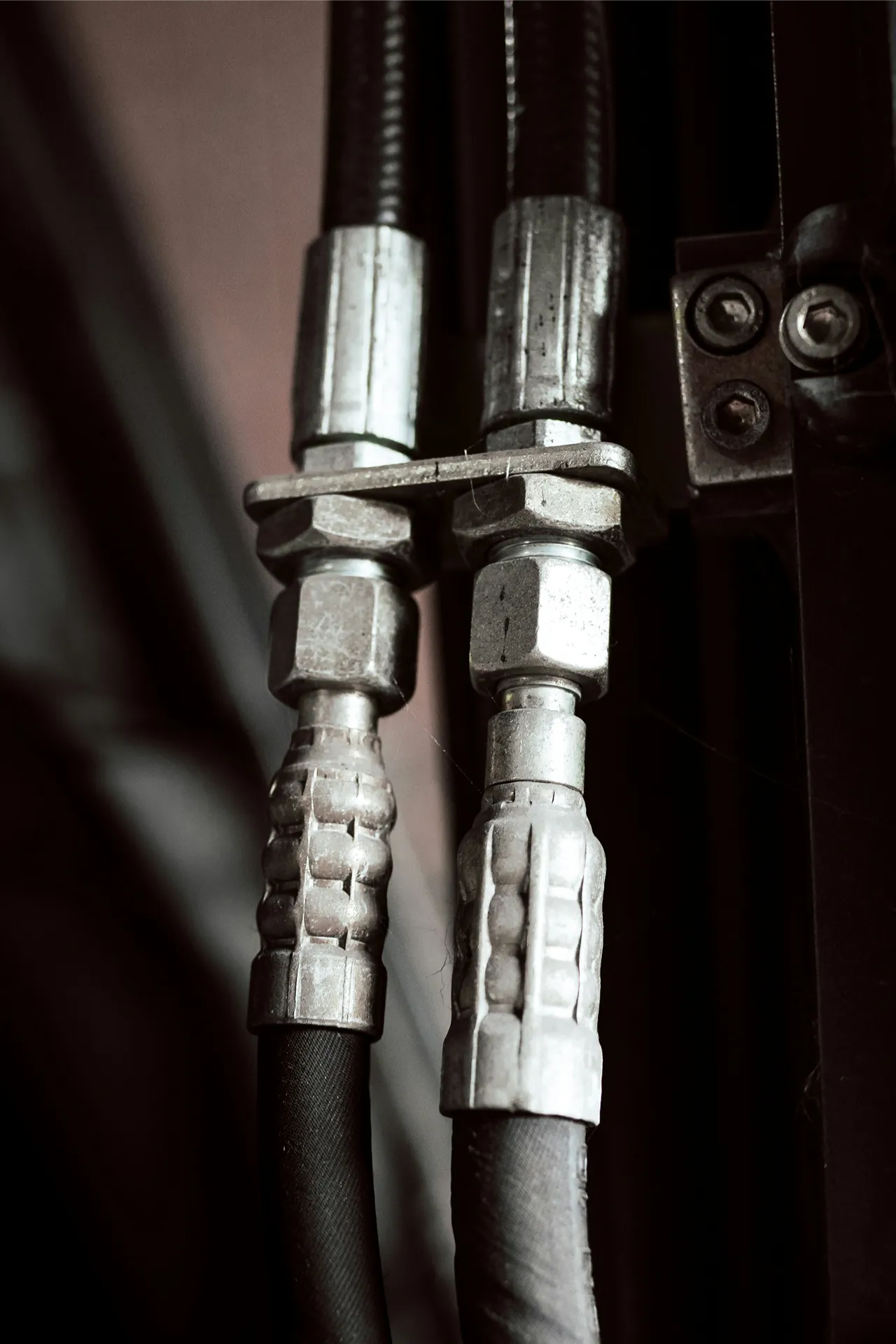 Hydraulic repair service for heavy-duty equipment, showing two high-pressure hoses with metal fittings and secure connections.