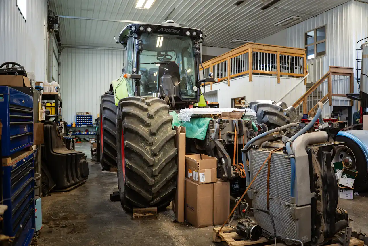 Heavy-duty equipment repair with an AXION tractor in a shop beside removed cooling components, hoses and parts.