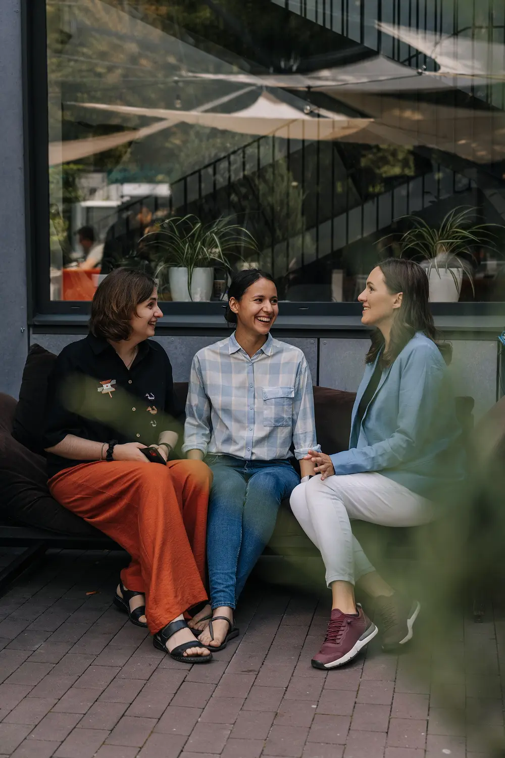 An outdoor scene featuring Tetiana Kobzar, CEO of Diversido, sitting with two colleagues on a cozy bench