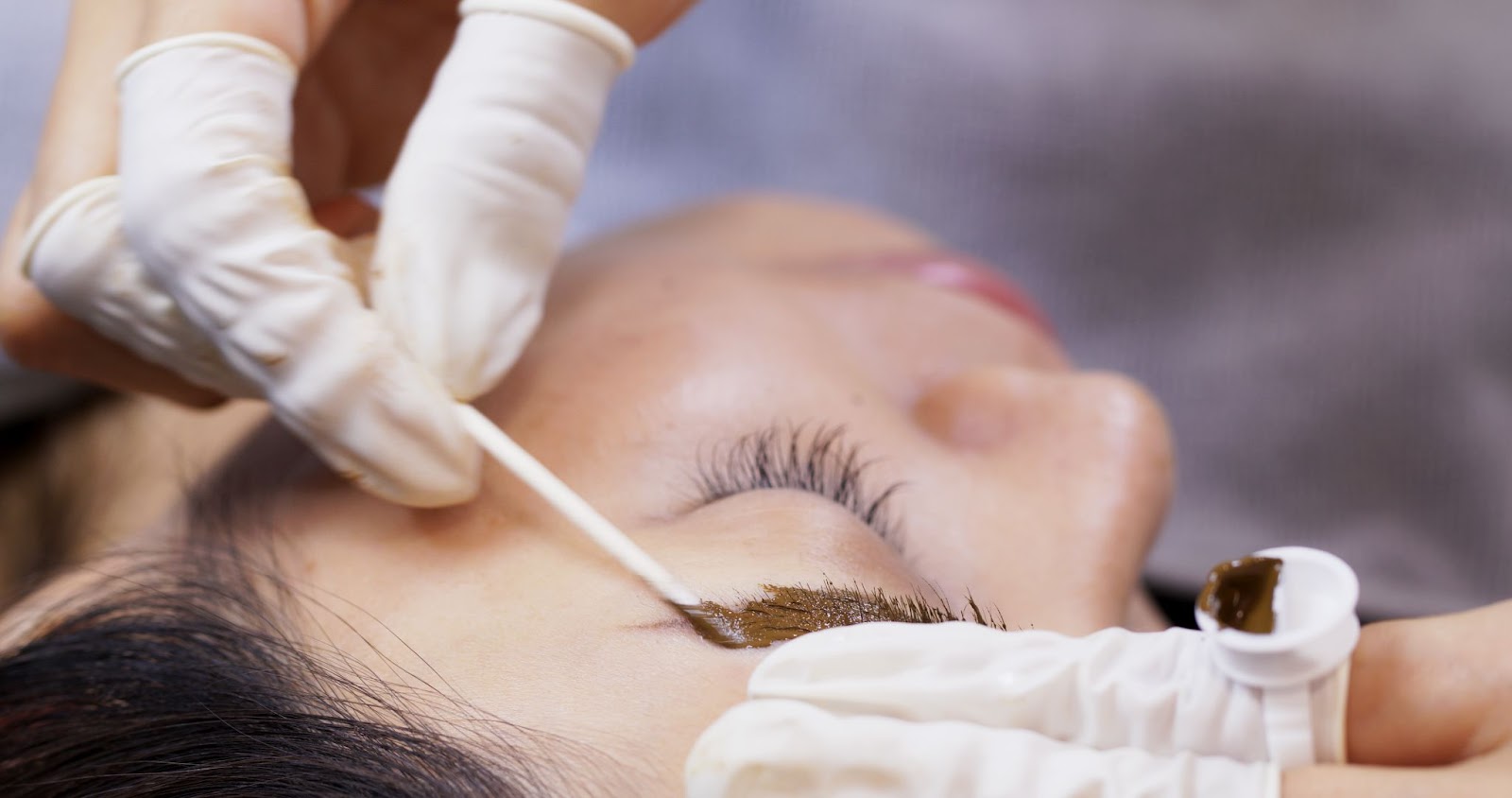 Close-up of expert brow tint application on a woman's eyebrow