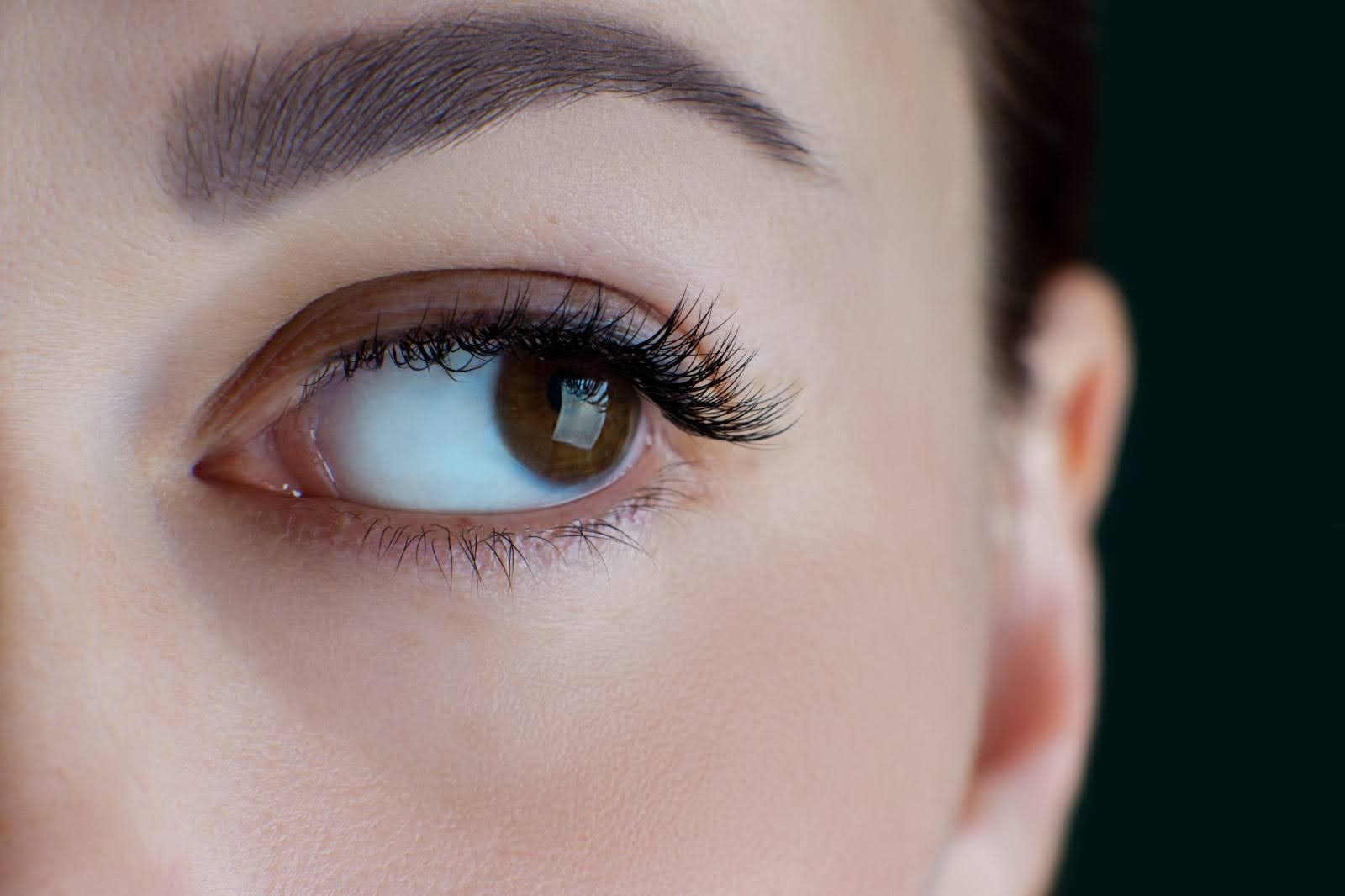 Close-up of a brown eye with lifted, ultra-long natural lashes after a lash lift treatment.