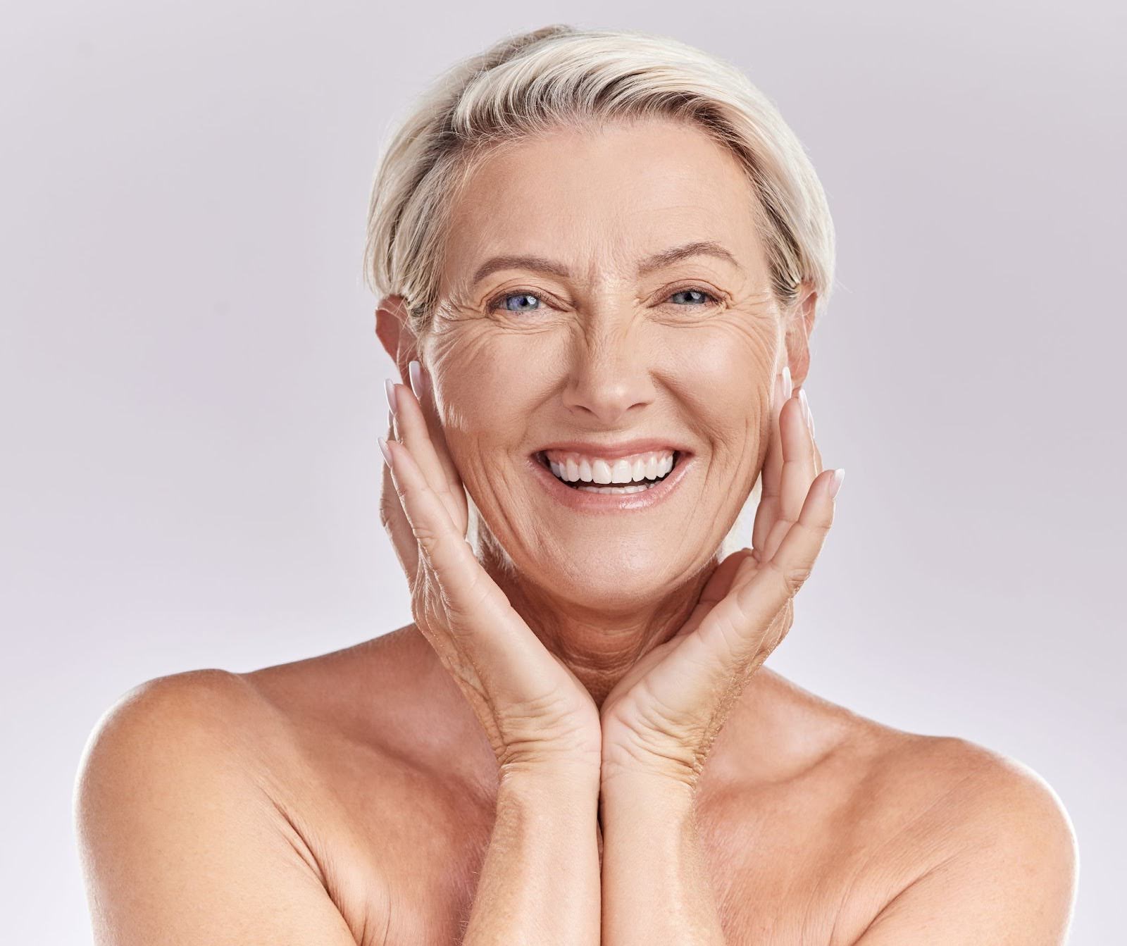 Smiling middle-aged woman touching her face showing the effects of microneedling.