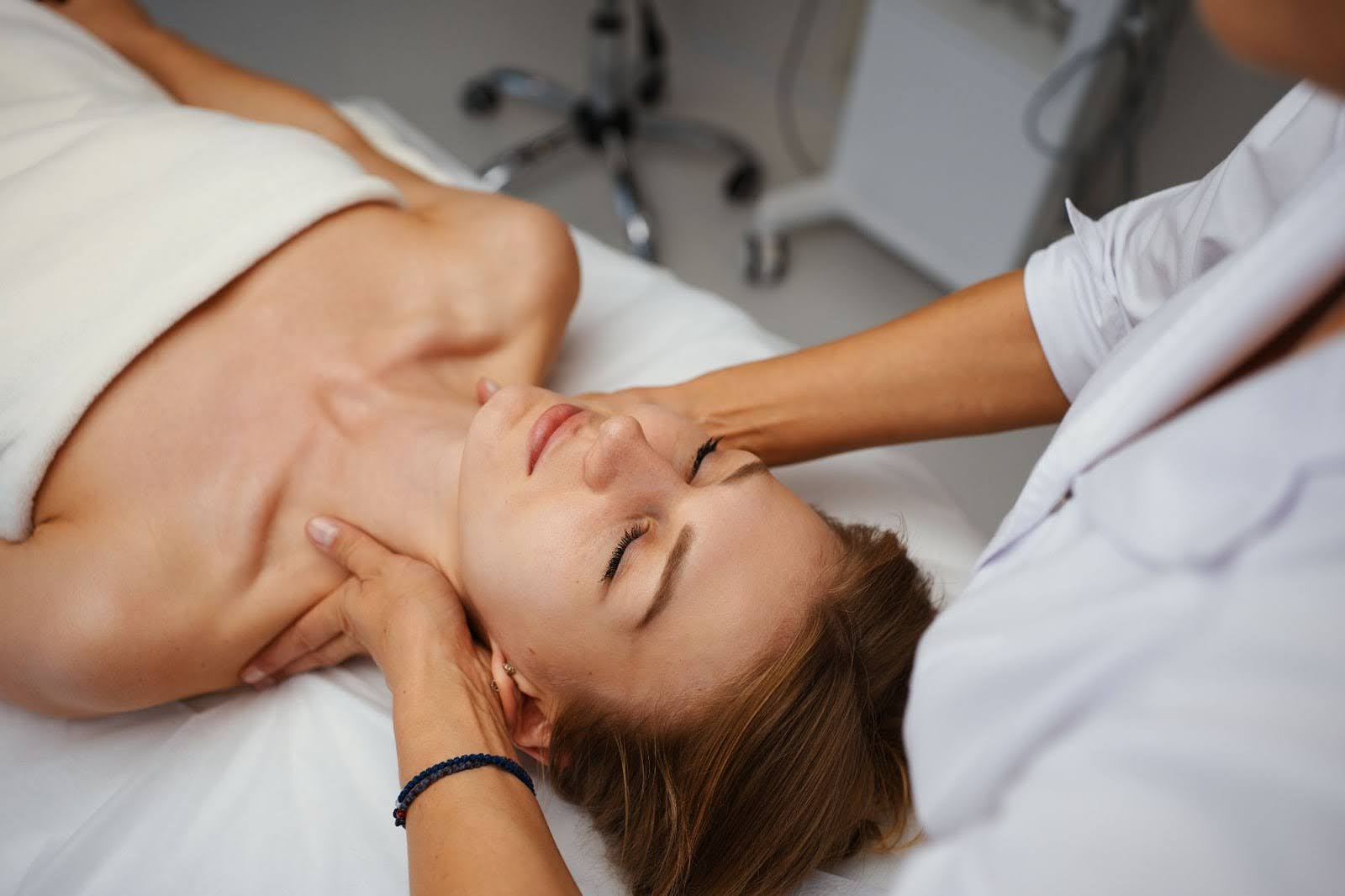 Young woman enjoying a professional lymphatic drainage neck massage at a wellness spa.
