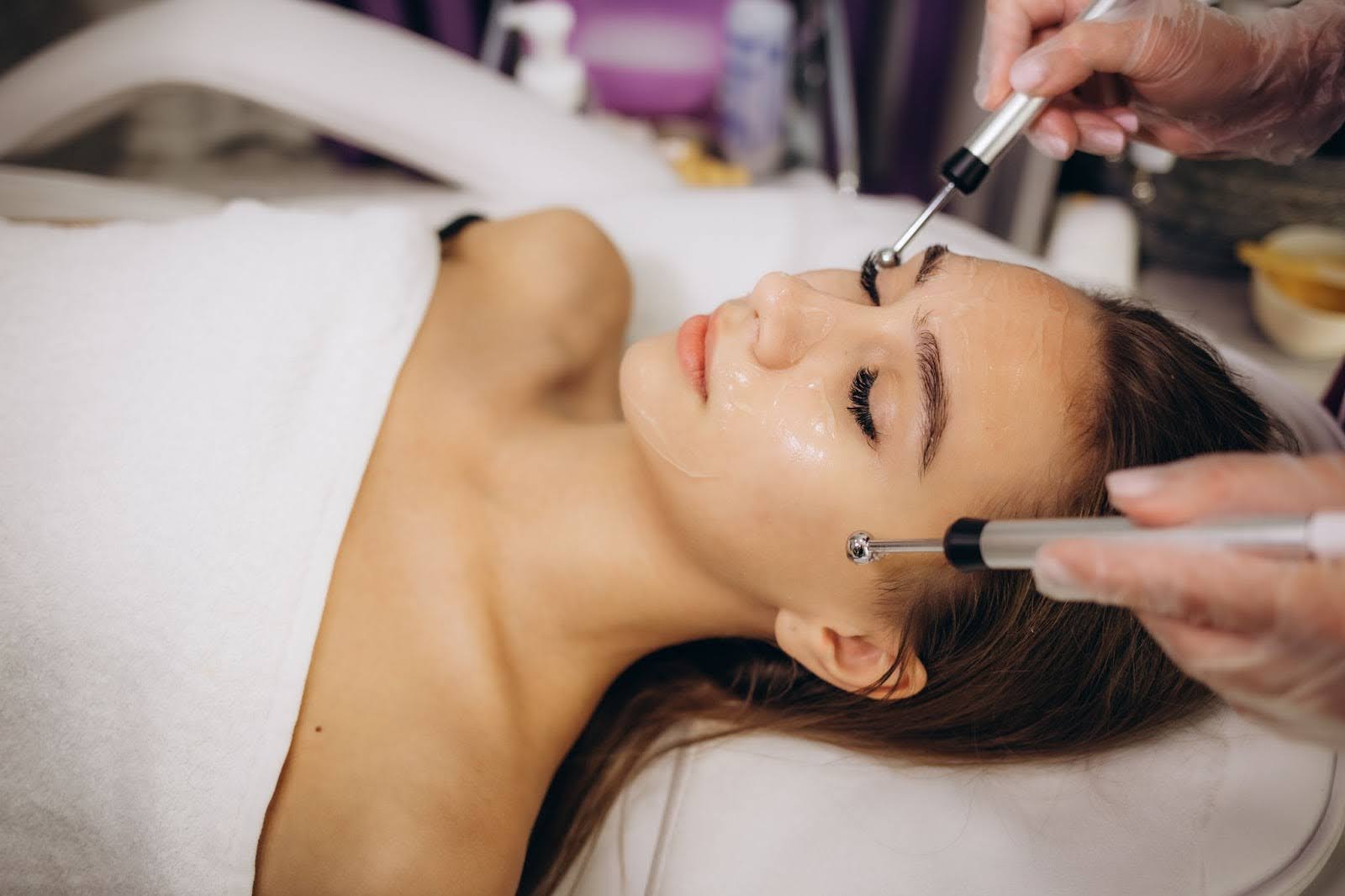A woman is relaxing while receiving facial treatments.