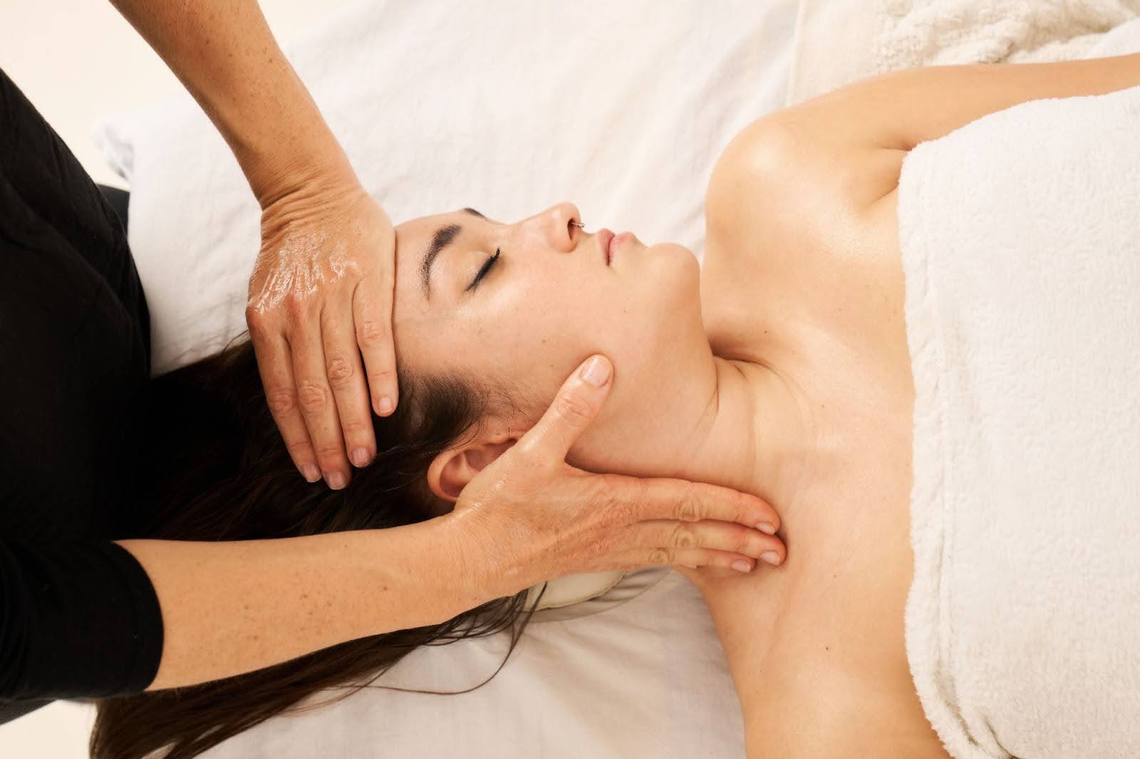 Woman receiving a lymphatic drainage facial massage focused on the cervical area to relieve tension and enhance lymph flow.