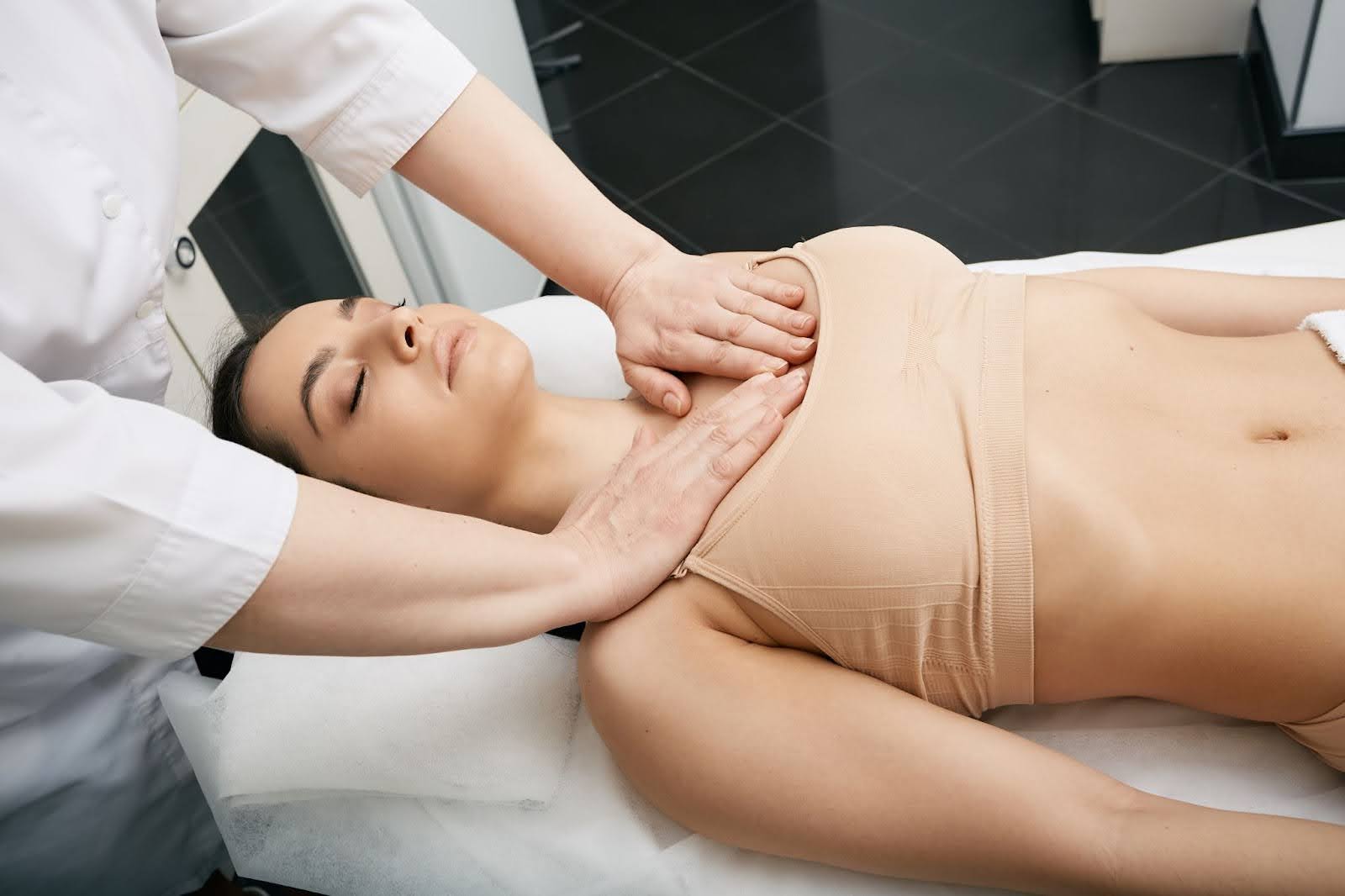 A therapist performs a lymphatic drainage massage on a woman’s chest to promote firmer, more resilient skin and improved circulation.