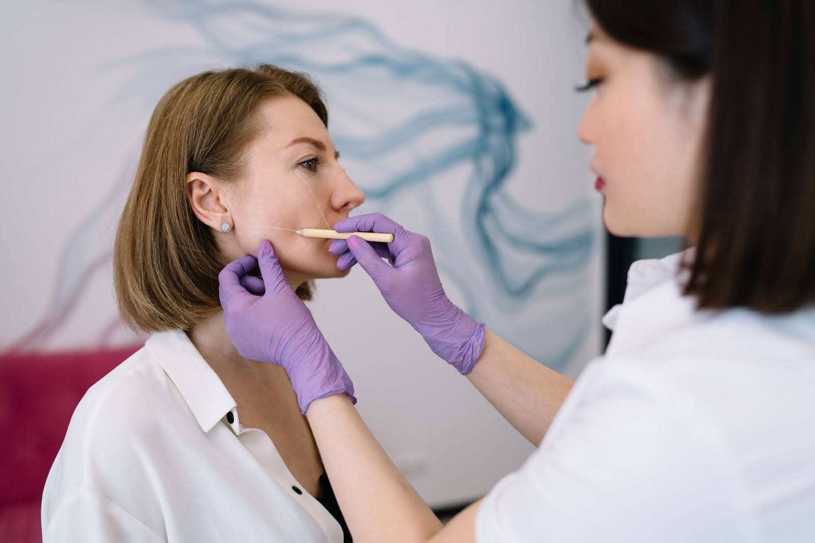 Professional aesthetician evaluating skin texture and symmetry before dermal filler treatment.