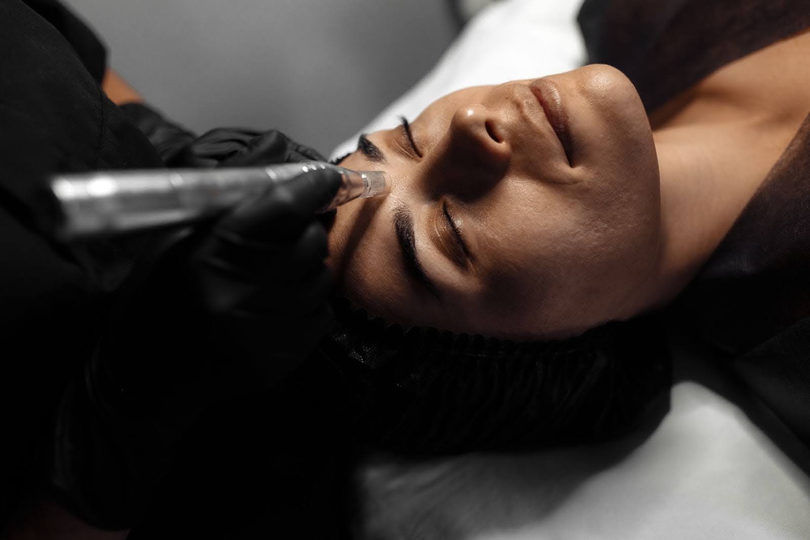 Aesthetician performing a precise skin cleansing procedure using a tool.