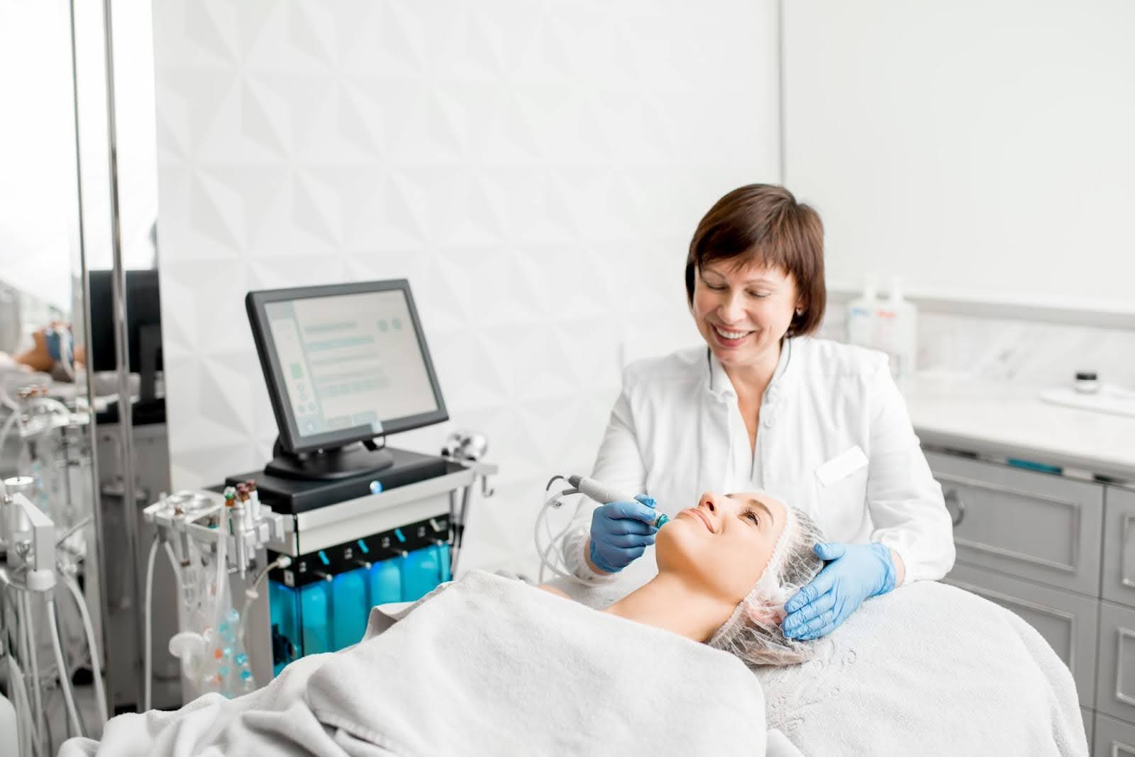 Experienced skincare specialist carrying out a Hydrafacial procedure for a female client.