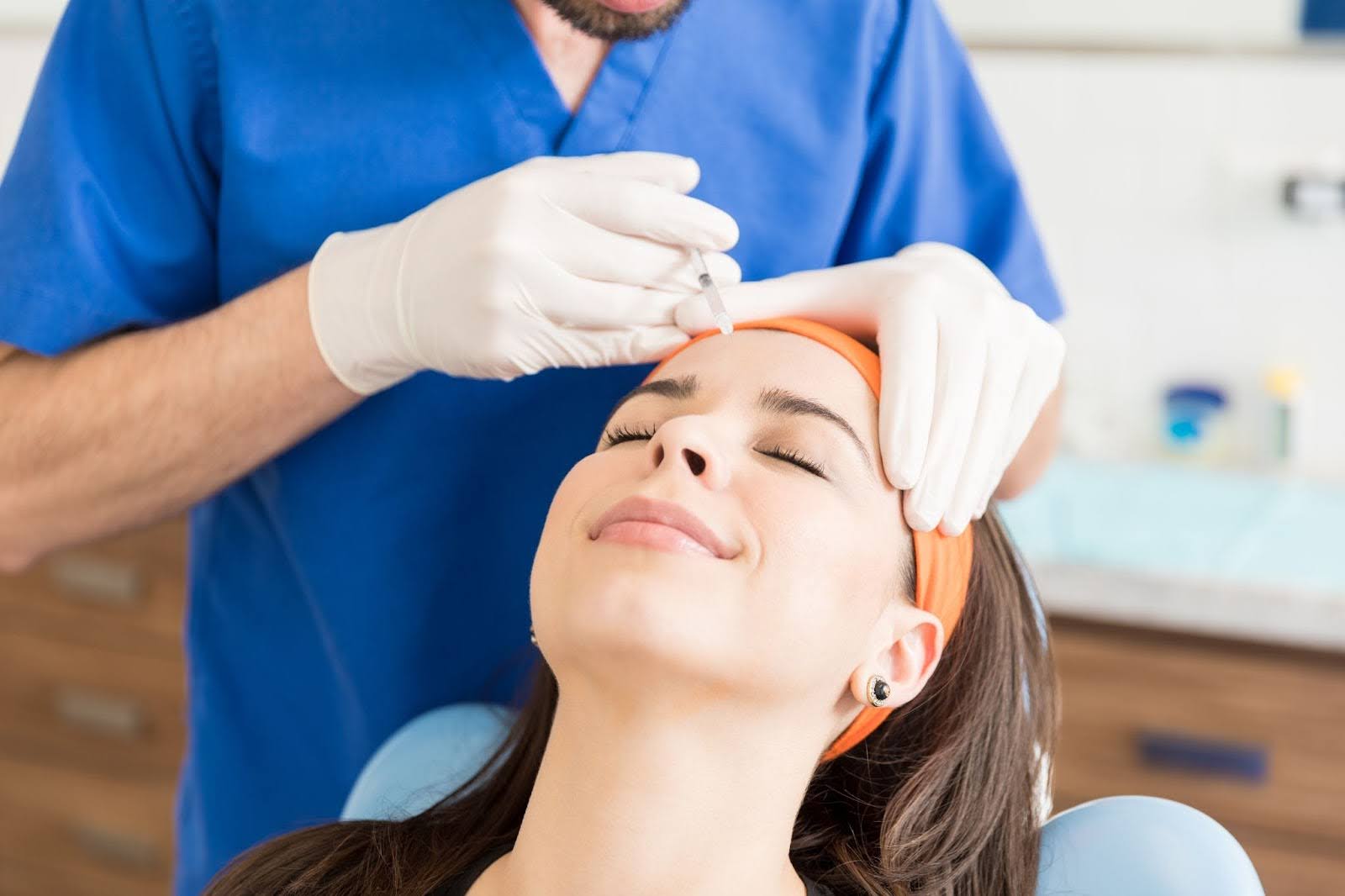 An aesthetician administering a Botox® forehead injection to smooth visible wrinkles.