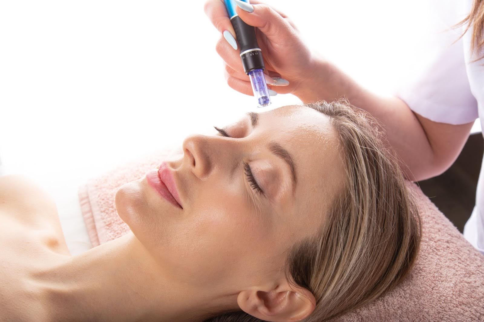 Female client receiving a professional microneedling pen treatment for skin rejuvenation.