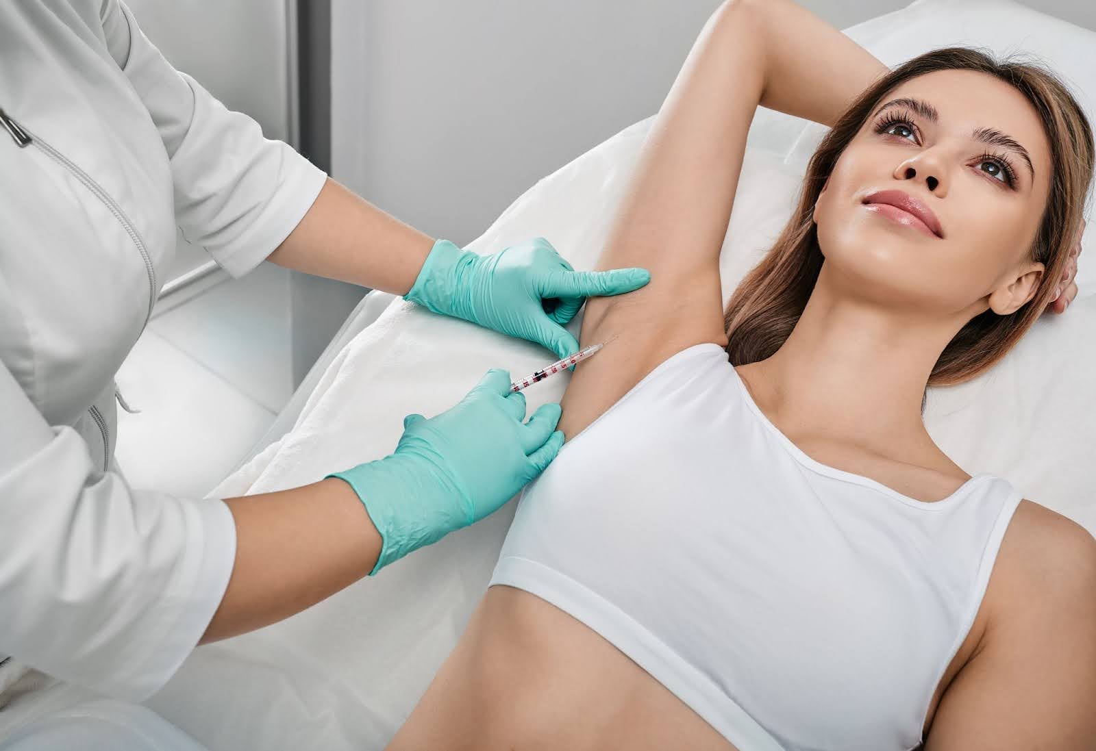 Female patient receiving underarm injections to manage excessive sweating.