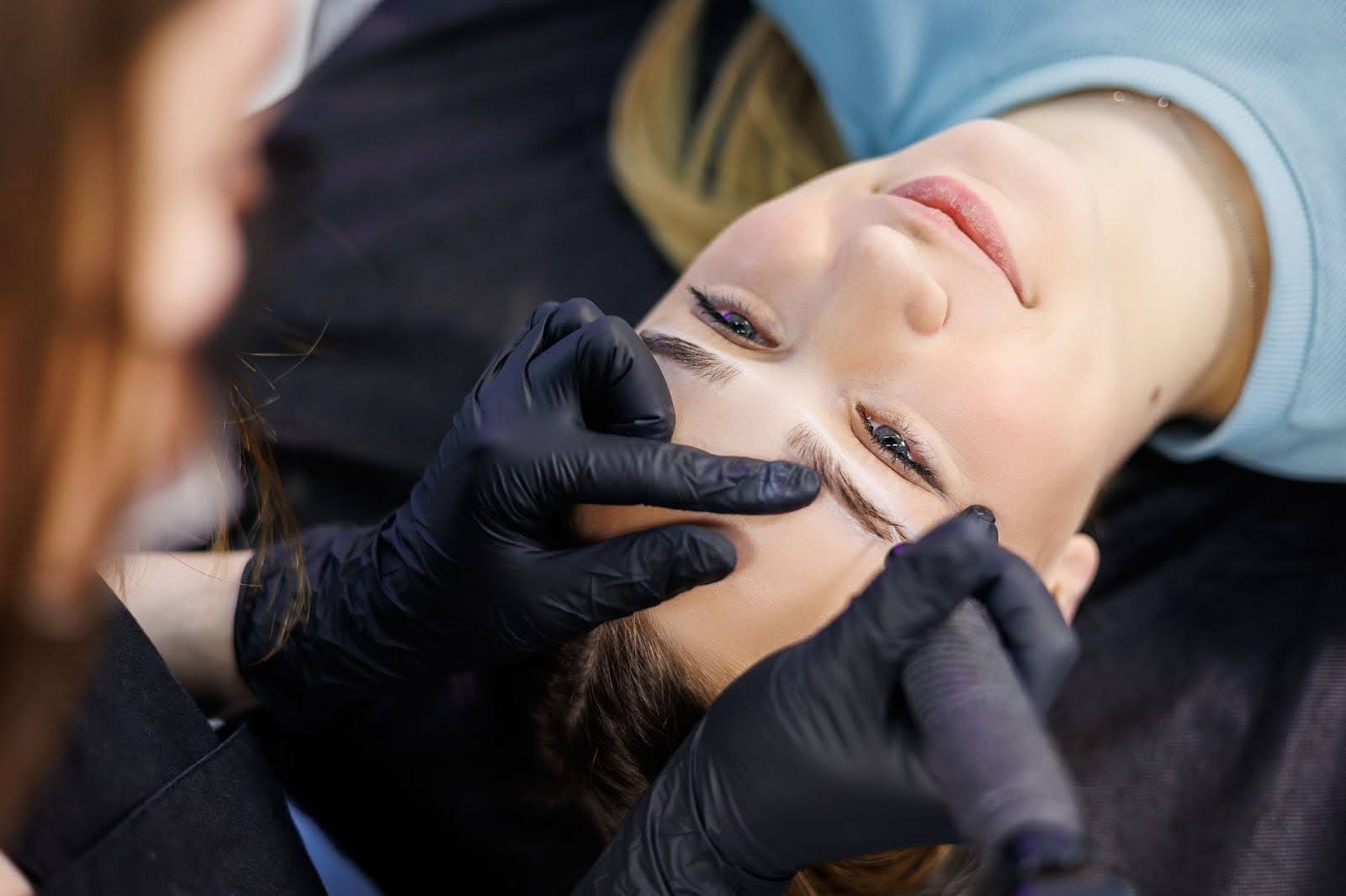 Licensed technician using a precision tool to prepare a client’s brows for lamination.