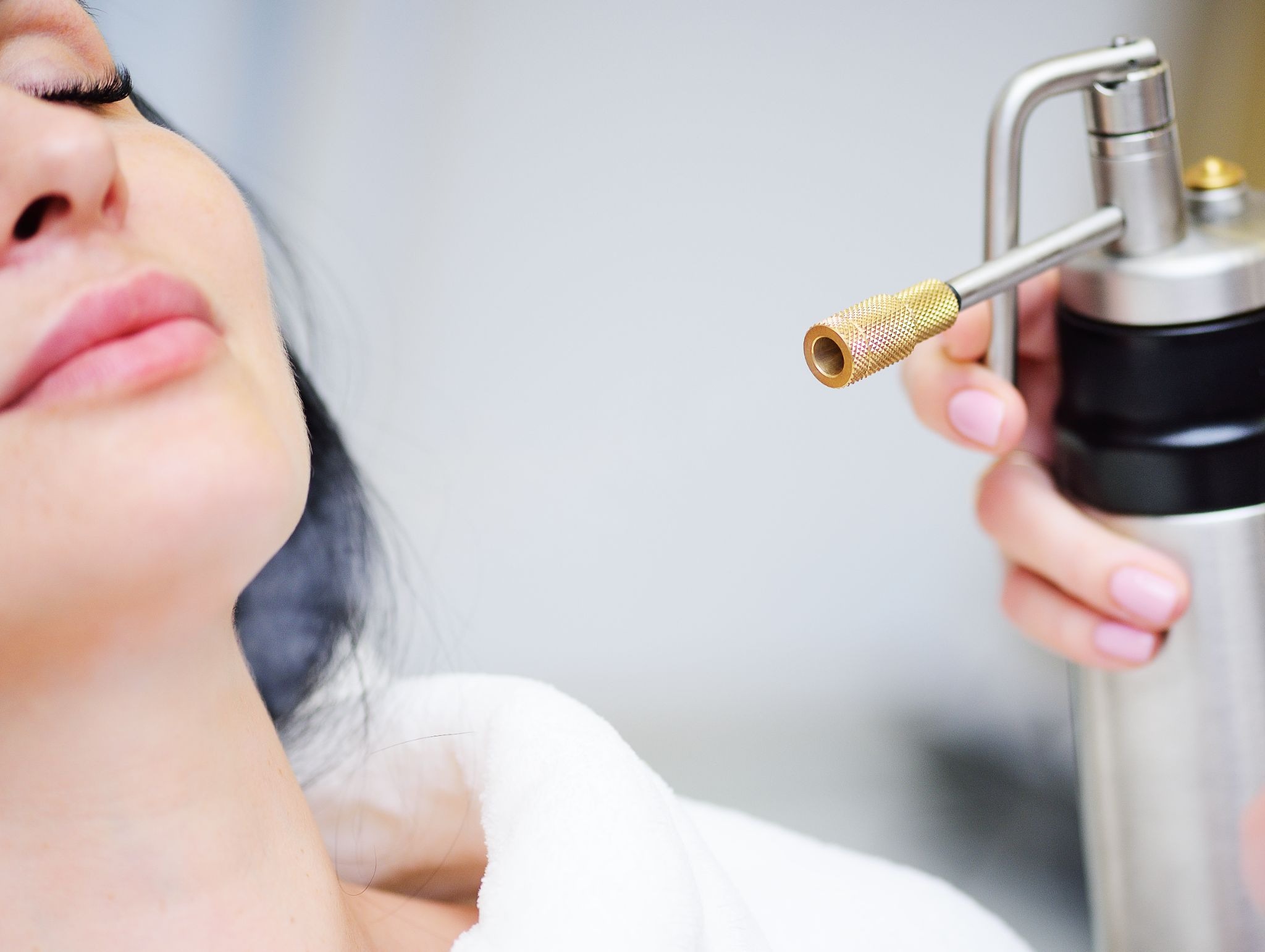 Aesthetic specialist applying oxygen therapy treatment to a patient during a professional facial session