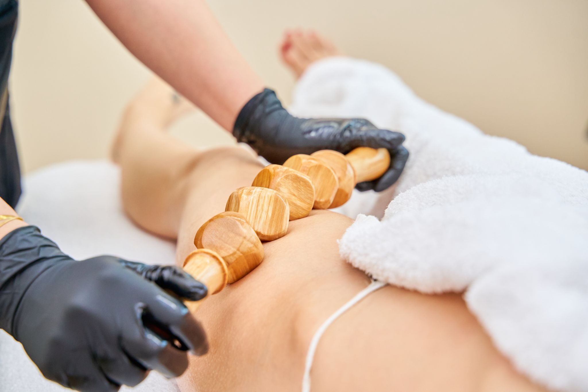 Woman undergoing lymphatic drainage treatment with a wooden tool to promote fluid movement