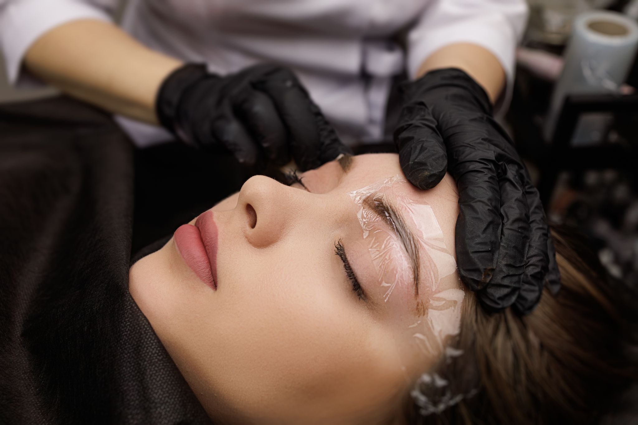 Woman receiving eyebrow lamination treatment for fuller, lifted brows