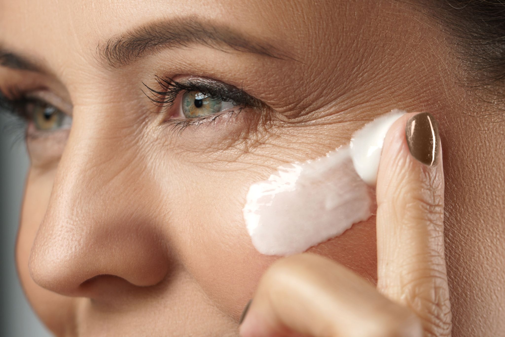 Close-up of a woman applying sunscreen on her face near the delicate eye area