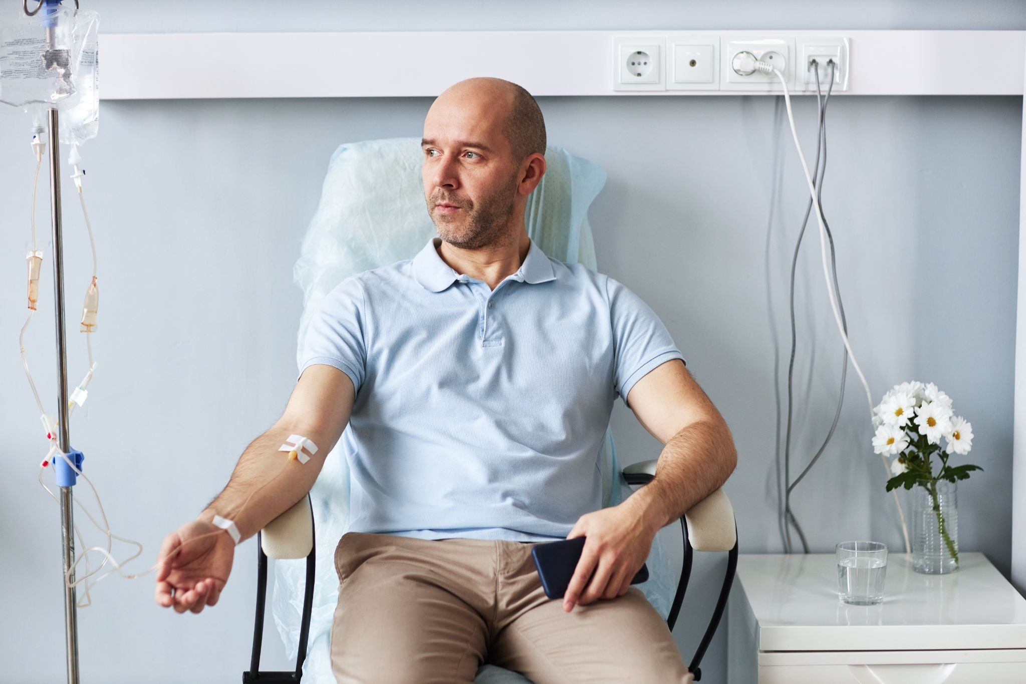 A man sits in a clinic chair receiving an IV drip during a treatment session