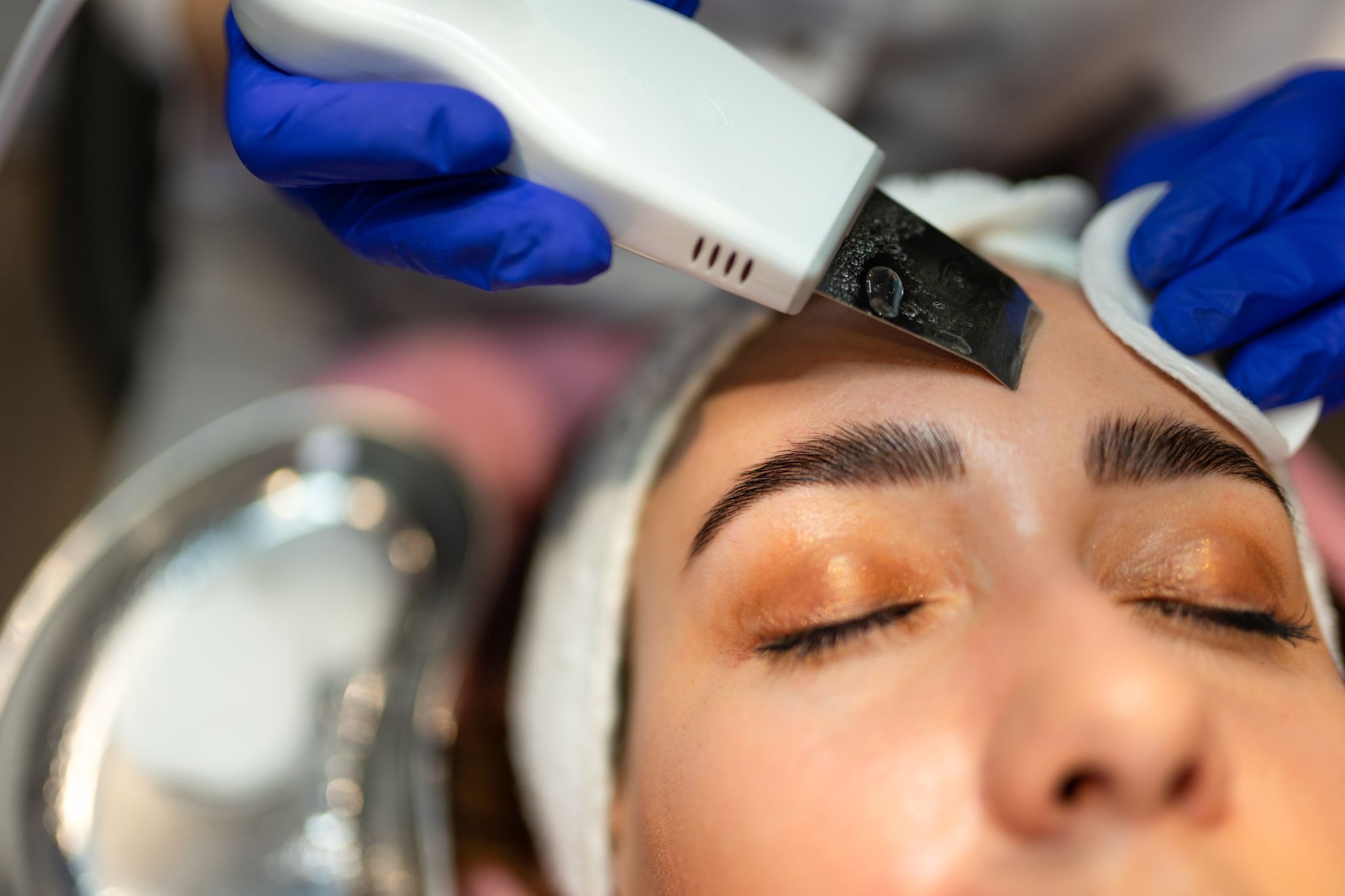 Close-up of a facial procedure on a woman’s forehead, removing dead skin and fine hair