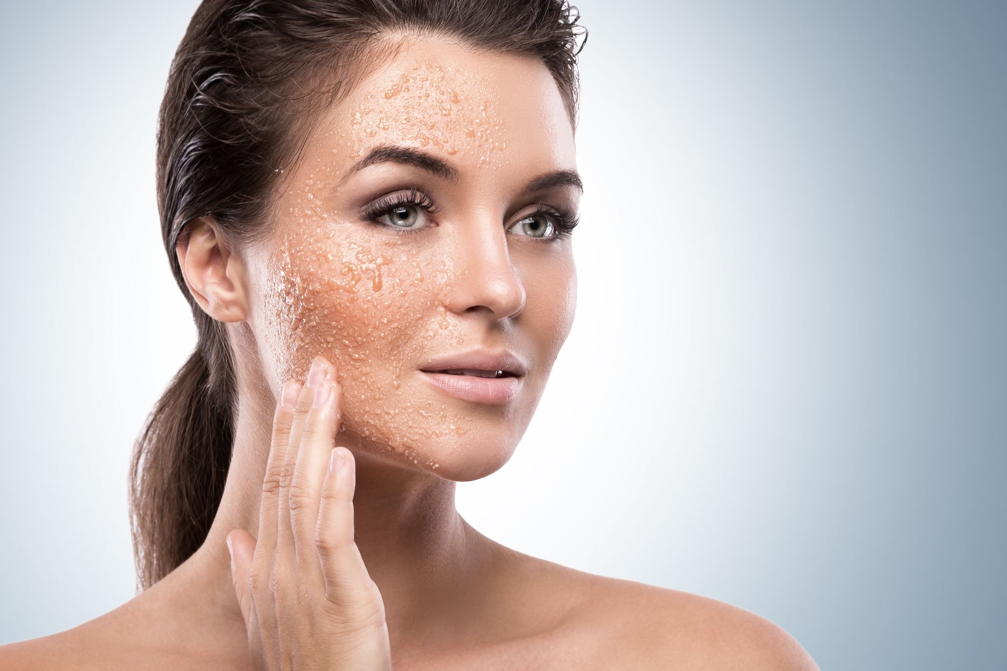 Woman applying gentle facial exfoliator to reduce pigmentation and brighten skin tone