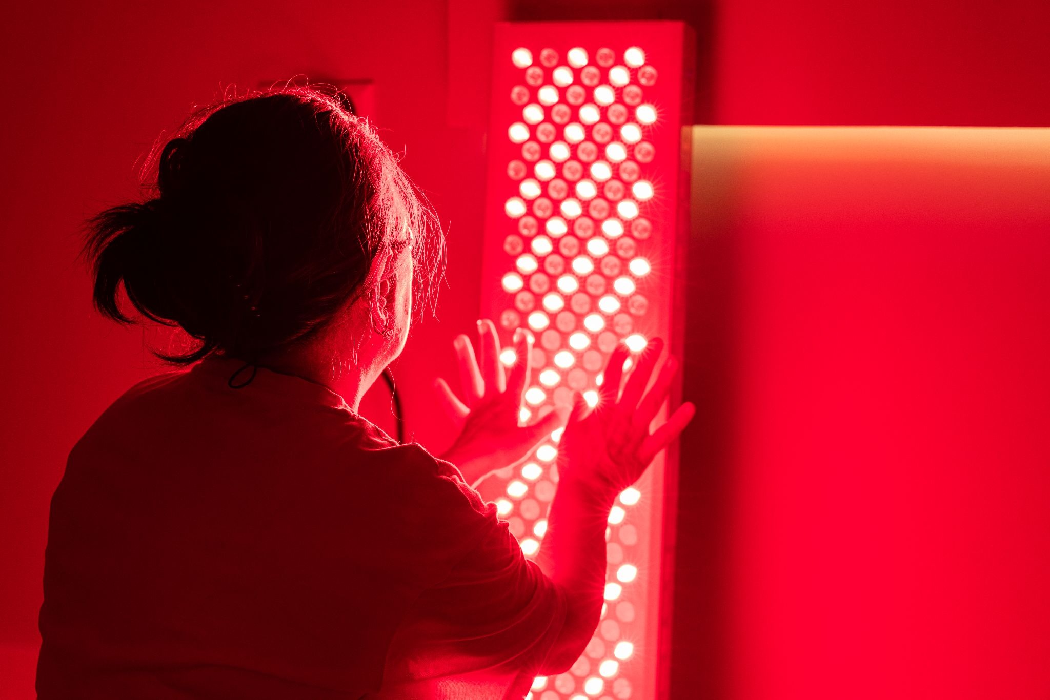 Rear view of a senior woman during red light therapy for muscle repair and overall wellness