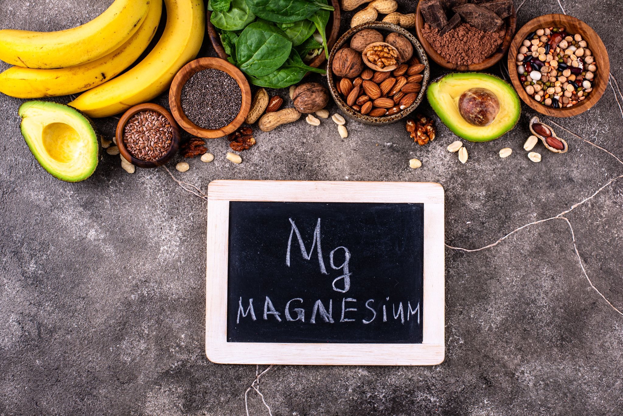 Magnesium-rich foods with a chalkboard displaying the word “magnesium” and its chemical symbol Mg