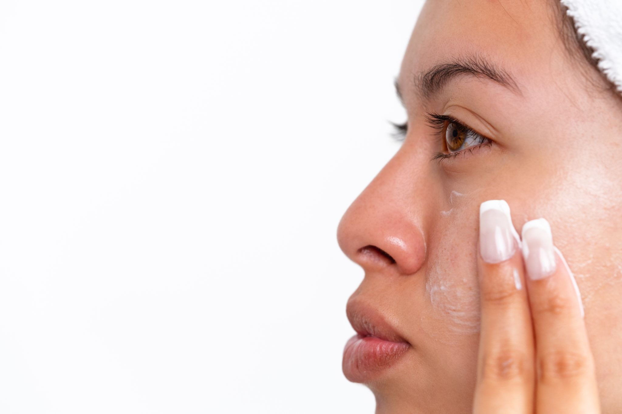 Woman applying skincare cream to her face to improve skin texture and reduce the appearance of pores