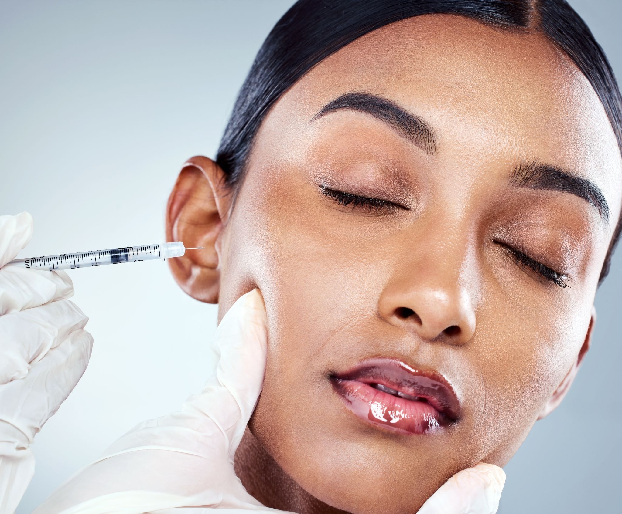 Woman receiving injectable fillers in the cheek area for volume enhancement