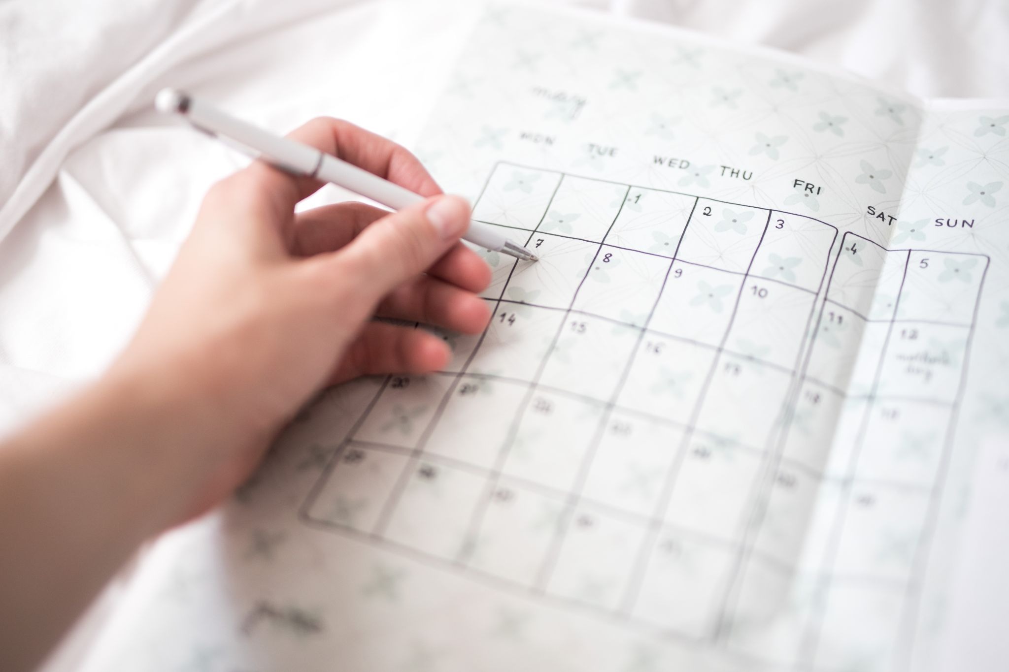  A hand writing future dermaplaning appointments on a calendar to maintain a consistent skincare routine