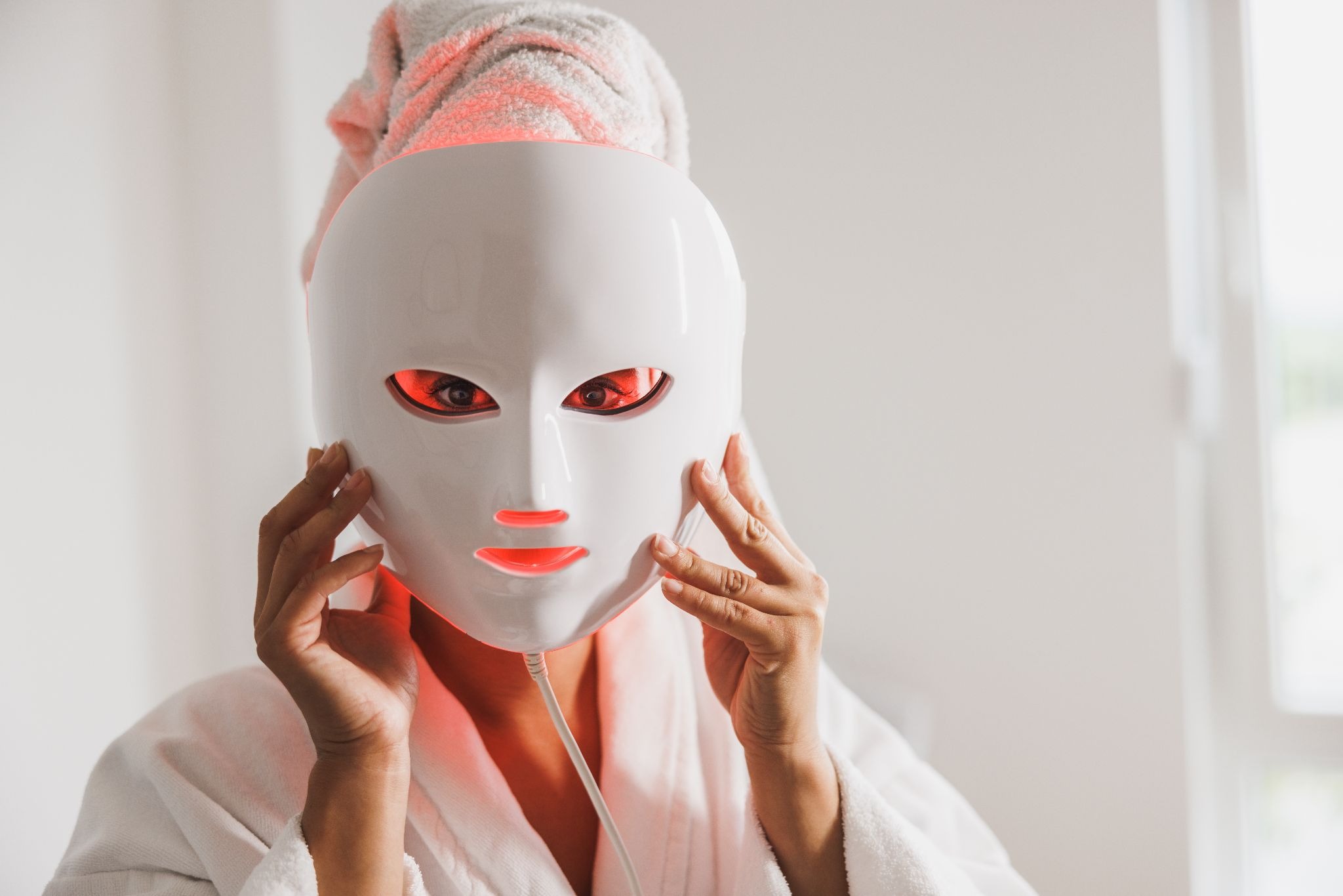 Woman wearing an LED light therapy facial mask during a skincare treatment