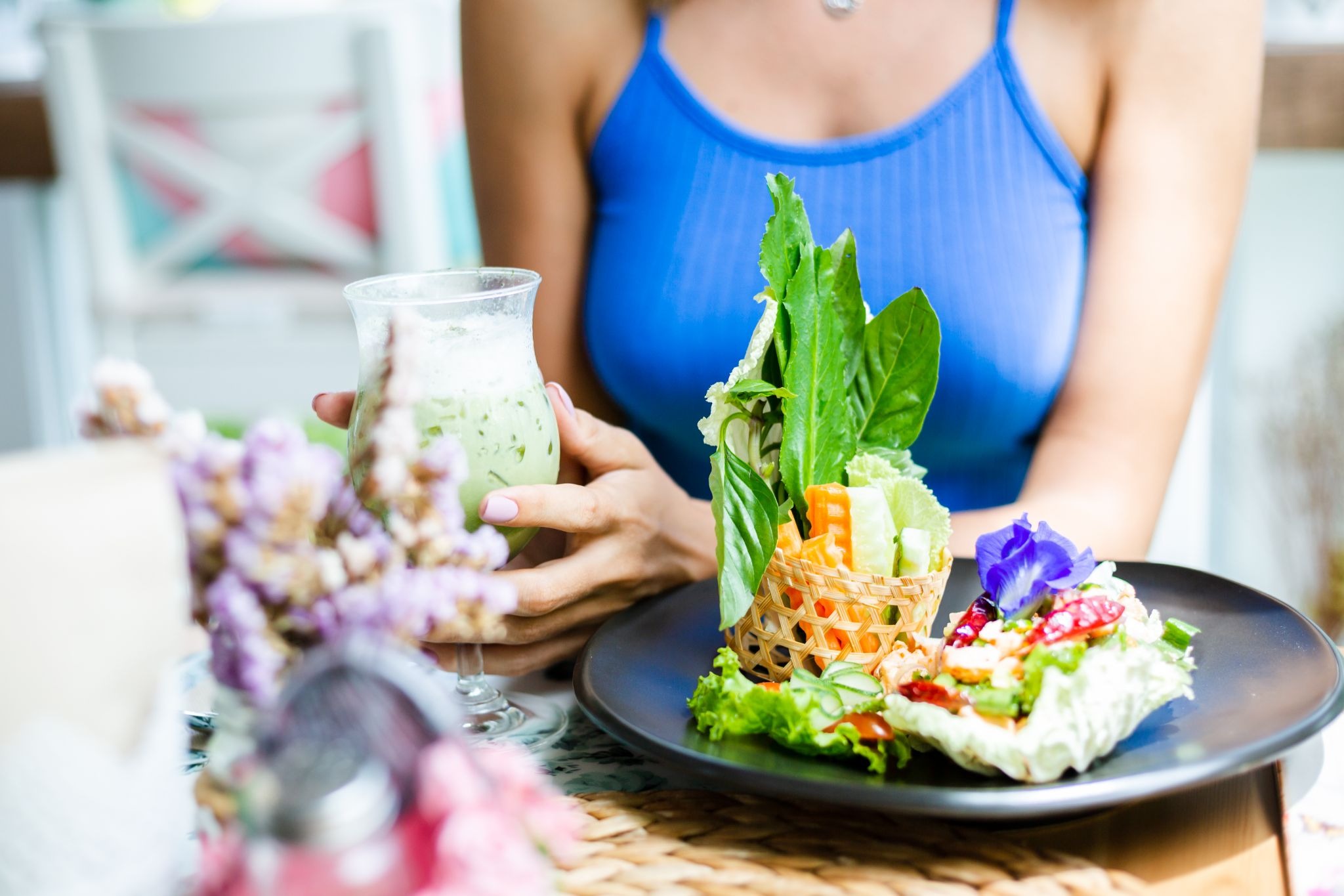 Cropped view of a woman enjoying a healthy salad and green drink to support post-microneedling skin recovery‍
